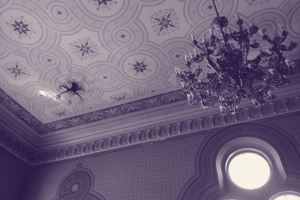 Le plafond décoré et le lustre d'une salle solennelle d'établissement scolaire.